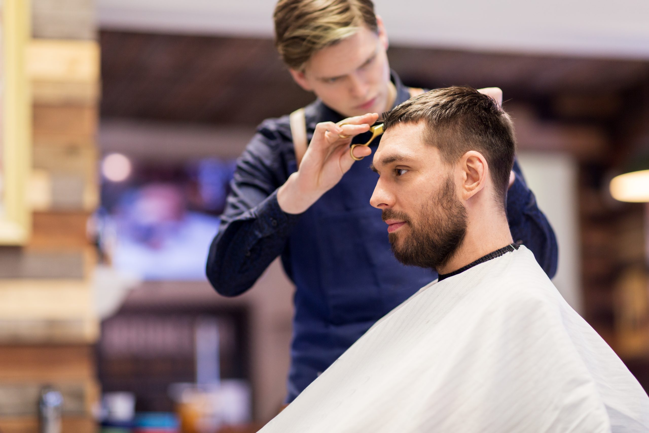 man and barber cutting hair at barbershop